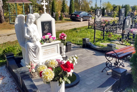 Сидящая на мраморной тумбе белая статуя ангела
